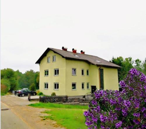 una gran casa amarilla con flores púrpuras delante de ella en HomeW4 - Rosen Apartment, en Hoheneich
