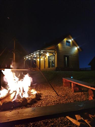 a fire in front of a cabin at night at Domek w sercu Kaszub in Dziemiany