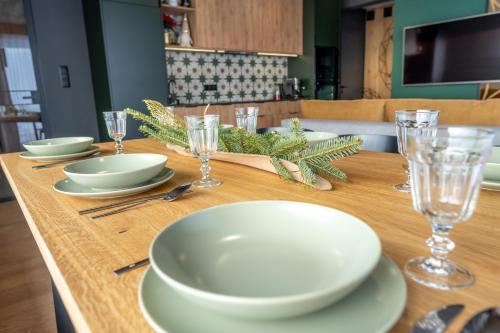 a wooden table with white plates and glasses on it at To Je To apartamenty in Maniowy