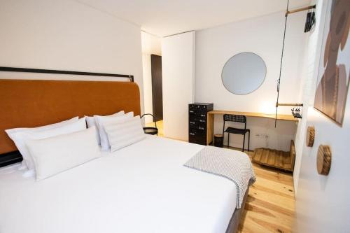 a bedroom with a large white bed and a desk at Dark Studio in São Roque