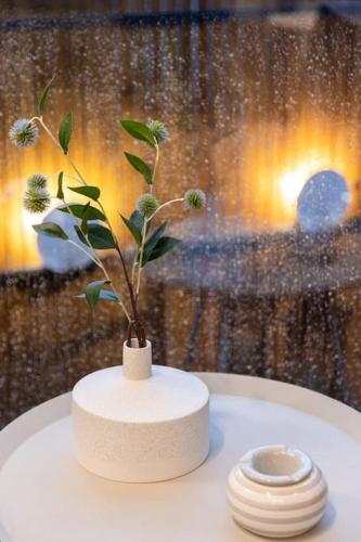 a white vase with a plant on top of a table at Dark Studio in São Roque