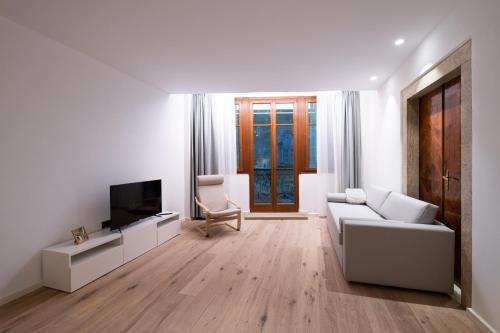 a white living room with a white couch and a tv at Palazzo Chimelli in Pergine Valsugana