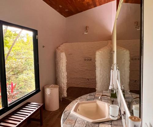 uma casa de banho com um lavatório e um piano ao lado de uma janela em Blue Banyan Inn em Quepos