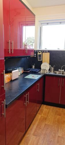 eine Küche mit roten Schränken und einem großen Fenster in der Unterkunft Crittlewood Guest House in Morton