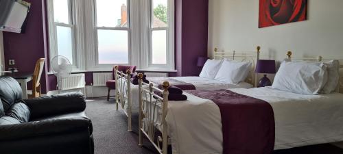 two beds in a room with purple walls and windows at Crittlewood Guest House in Morton