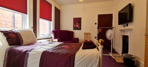 a bedroom with a bed and a chair and a fireplace at Crittlewood Guest House in Morton