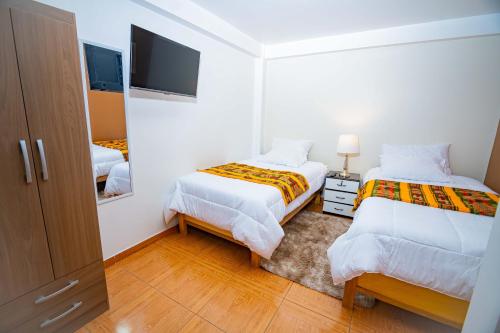een witte kamer met 2 bedden en een televisie bij Departamento KIRI familiar ó empresarial cerca al Aeropuerto de Juliaca- Perú in Juliaca