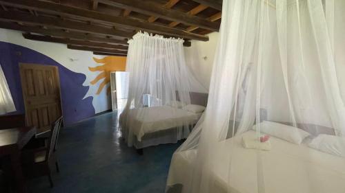 a bedroom with two beds with white drapes at Casa Yuluka en la playa, Palomino in Palomino