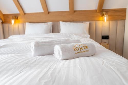 a white bed with a towel on top of it at To Je To apartamenty in Maniowy