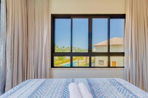 um quarto com uma cama e uma grande janela em SA07 Maravilhosa Casa 5 Suítes - Reserva de Sauípe na Costa do Sauípe