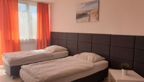 two beds in a room with orange curtains at Workers-Sleep-Station in Cologne
