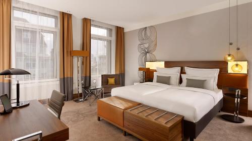 a bedroom with a large white bed and a desk at Reichshof Hotel Hamburg in Hamburg
