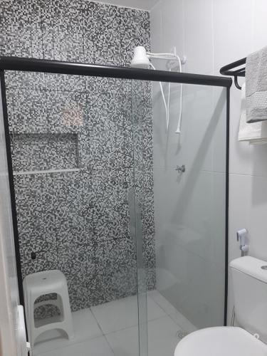 uma casa de banho com uma cabina de duche em vidro e um WC. em Suítes flor de Mandacaru em Piranhas