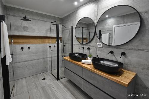 a bathroom with two sinks and two mirrors at אחוזת שקד בוטיק - מתחם פרטי 3 חדרי שינה, בריכה מחוממת , ג'קוזי ונוף בגליל המערבי in ‘Ein Ya‘aqov