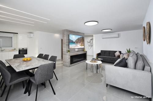 a living room with a couch and a table with chairs at אחוזת שקד בוטיק - מתחם פרטי 3 חדרי שינה, בריכה מחוממת , ג'קוזי ונוף בגליל המערבי in ‘Ein Ya‘aqov