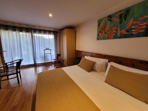 a bedroom with a large bed and a large painting on the wall at Te Ariki - Adults Only in Hanga Roa