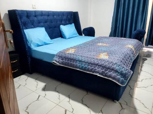 1 cama con edredón azul y almohadas azules en Kigali Center Apartment-1Bedroom, en Kigali