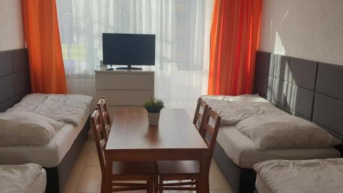 a room with two beds and a table and a tv at Workers-Sleep-Station in Cologne