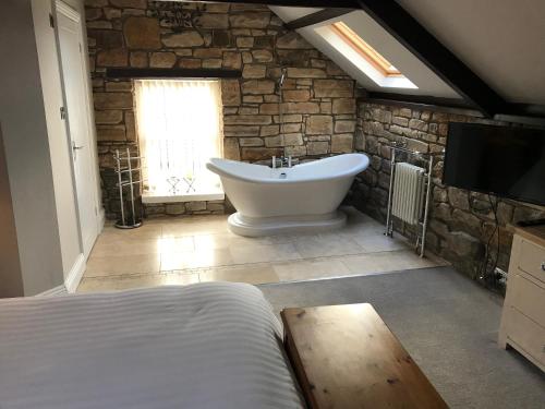 a bathroom with a tub and a tv in a room at Linden Studio in Morpeth
