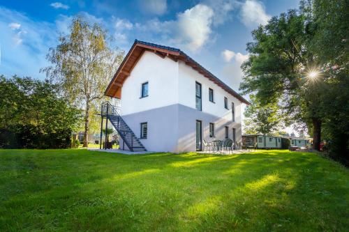 a white house with a gambrel roof on a green field at Apartament Marta in Kudowa-Zdrój