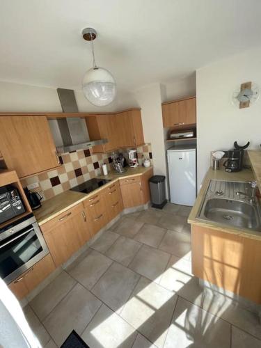 une cuisine avec un évier et une cuisinière four supérieur dans l'établissement Maison au sein d’un corps de ferme., à Carpiquet