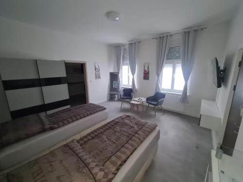 1 dormitorio con 2 camas, sillas y ventanas en Apartament Suite 1, en Bernburg