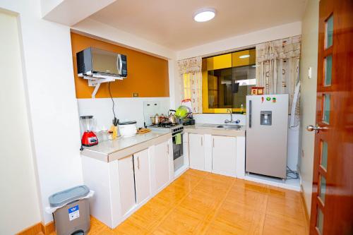a kitchen with white cabinets and a white refrigerator at Departamentos KIRI para familias o empresas que viajan en grupo cerca al Aeropuerto Juliaca in Juliaca