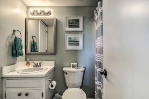 a bathroom with a toilet and a sink and a mirror at Condo with Pool Access - Walk to Beach! in Carolina Beach