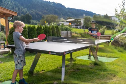 dos niños jugando ping pong en una mesa de ping pong en Hartlhof Urlaub am Baby- und Kinderbauernhof, en Niederau