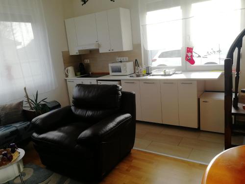 a living room with a black chair and a kitchen at Zsuzsanna Vendégház in Gyomaendrőd