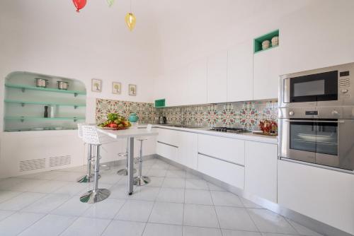 a kitchen with white cabinets and a table at Villa Tesoro in Positano