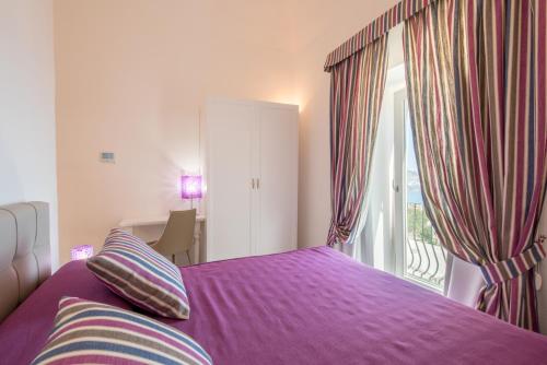 a bedroom with a purple bed and a balcony at Villa Tesoro in Positano