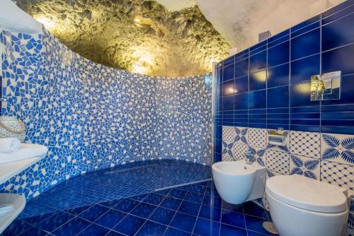 a blue tiled bathroom with a toilet and a sink at Villa Tesoro in Positano