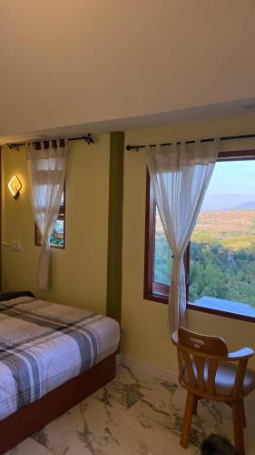 een slaapkamer met een bed, een stoel en een raam bij ภูคำฮ้อมคลิฟฟ์ลอดจ์ แอนด์ โฮมสเตย์ Phu come home cliff Lodge & Homestay in Ban Phu Hi