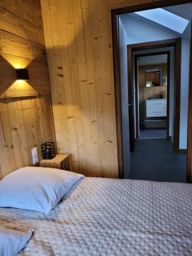 - une chambre avec un lit et un mur en bois dans l'établissement Beau duplex à proximité du lac de Gérardmer avec place de parking, à Gérardmer