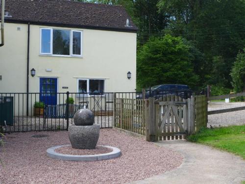 a fence in front of a house with a gate at The Rock self-catering holiday cottage and garden lodges in Coleford