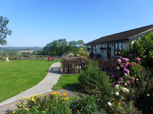 a house with a garden with flowers in front of it at The Rock self-catering holiday cottage and garden lodges in Coleford