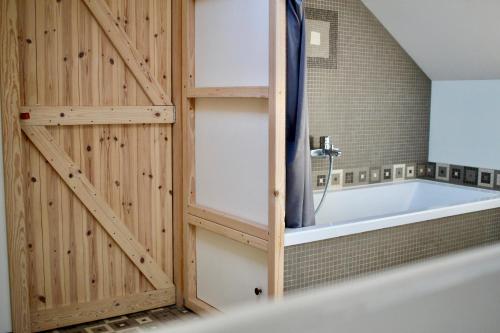 JodoigneにあるGîte l'Ecurieの木製の壁のバスルーム(バスタブ付)