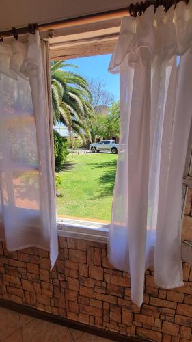 a window with white curtains and a view of a yard at Chalet Mar del Plata in Mar del Plata