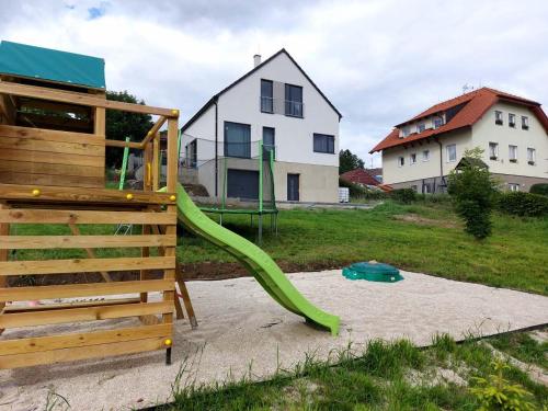 a green slide in the sand in front of a house at Lipnohaus in Horní Planá