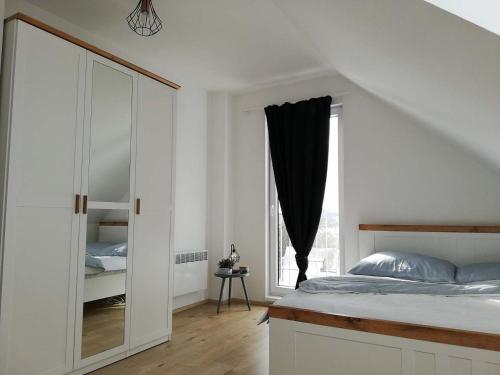 a white bedroom with a bed and a window at Lipnohaus in Horní Planá