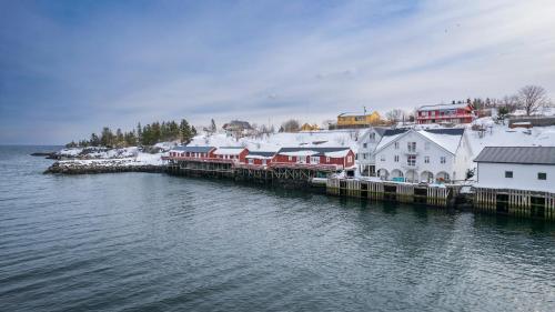 a small town with snow covered buildings next to the water at The Tide - Rorbuer in Sørvågen