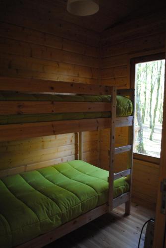 Ce lit superposé se trouve dans une cabane en rondins dotée d'une fenêtre. dans l'établissement Bungalows da Peneda, à Lamas de Mouro