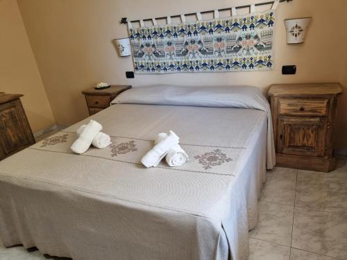 a bedroom with two beds with white sheets and towels at Hotel Plammas in Santa Maria Navarrese