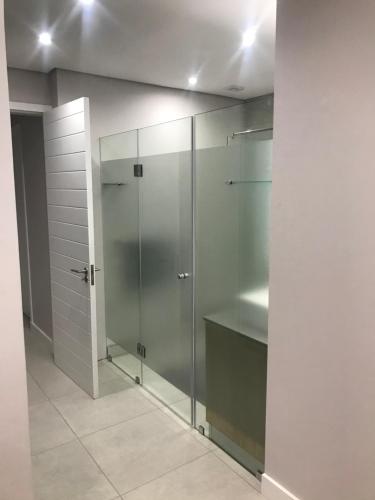 a bathroom with a glass walk in shower at Stylish Sea View Apartment in Santorini Estate. in Ballito