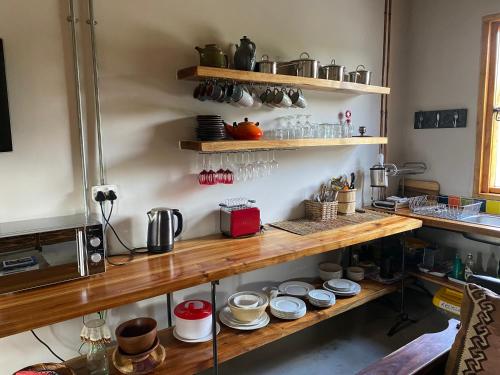 a kitchen with wooden shelves with pots and pans at The Ruskamer Cottage at In the End in Stanford