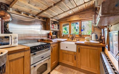 a kitchen with wooden cabinets and a white stove top oven at WOW! Jungle Cabin Hottub, 4 poster bed, Nr Coast in Martin