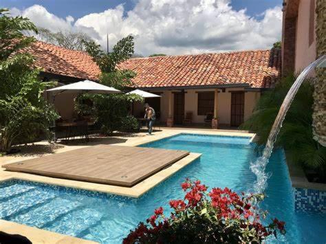 a swimming pool with a wooden deck next to a house at Hotel Hacienda La Fe in Bucaramanga