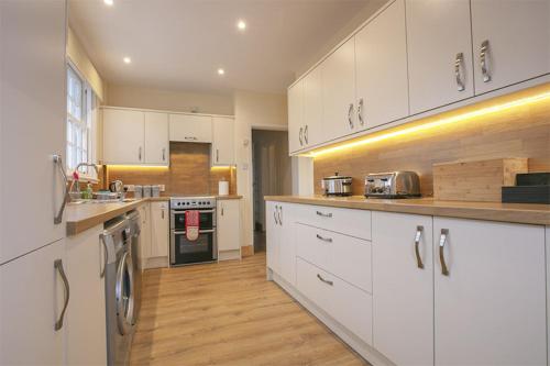 cocina grande con armarios blancos y suelo de madera en Craigievern Cottage, en Drymen