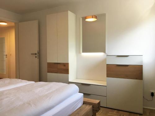 a bedroom with a white bed and a cabinet at Ferienwohnung Koje in Wees